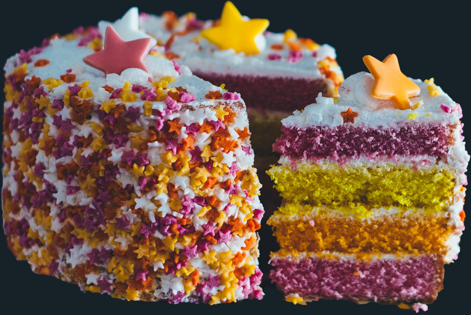 a large cake in bright pin, orange and yellow with a slice cut out